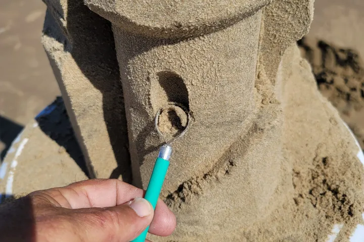 picture shows andy hancock of south padre island using one his advanced tools that uses a square profile to carve an intricate internal staircase inside a sandcastle